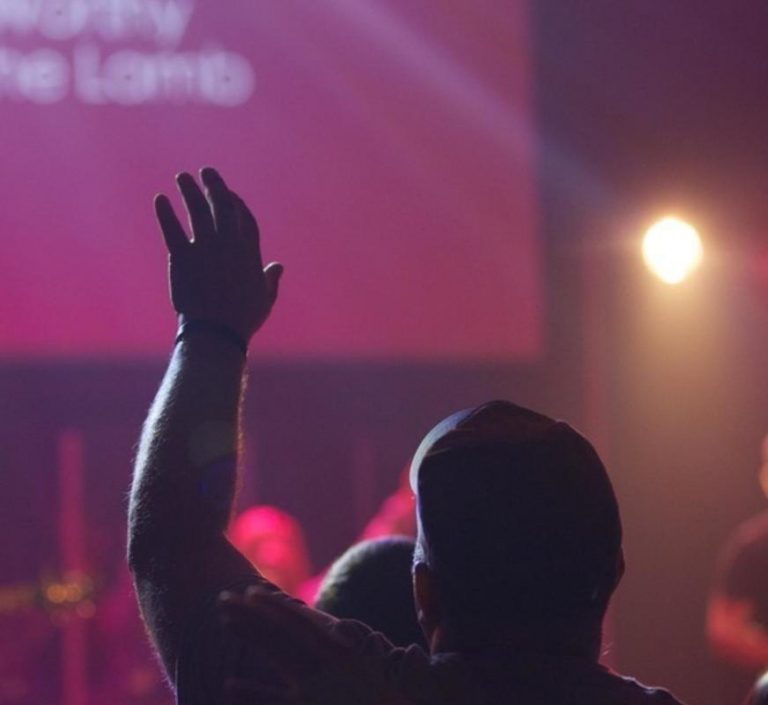 man lifting hand in worship during service